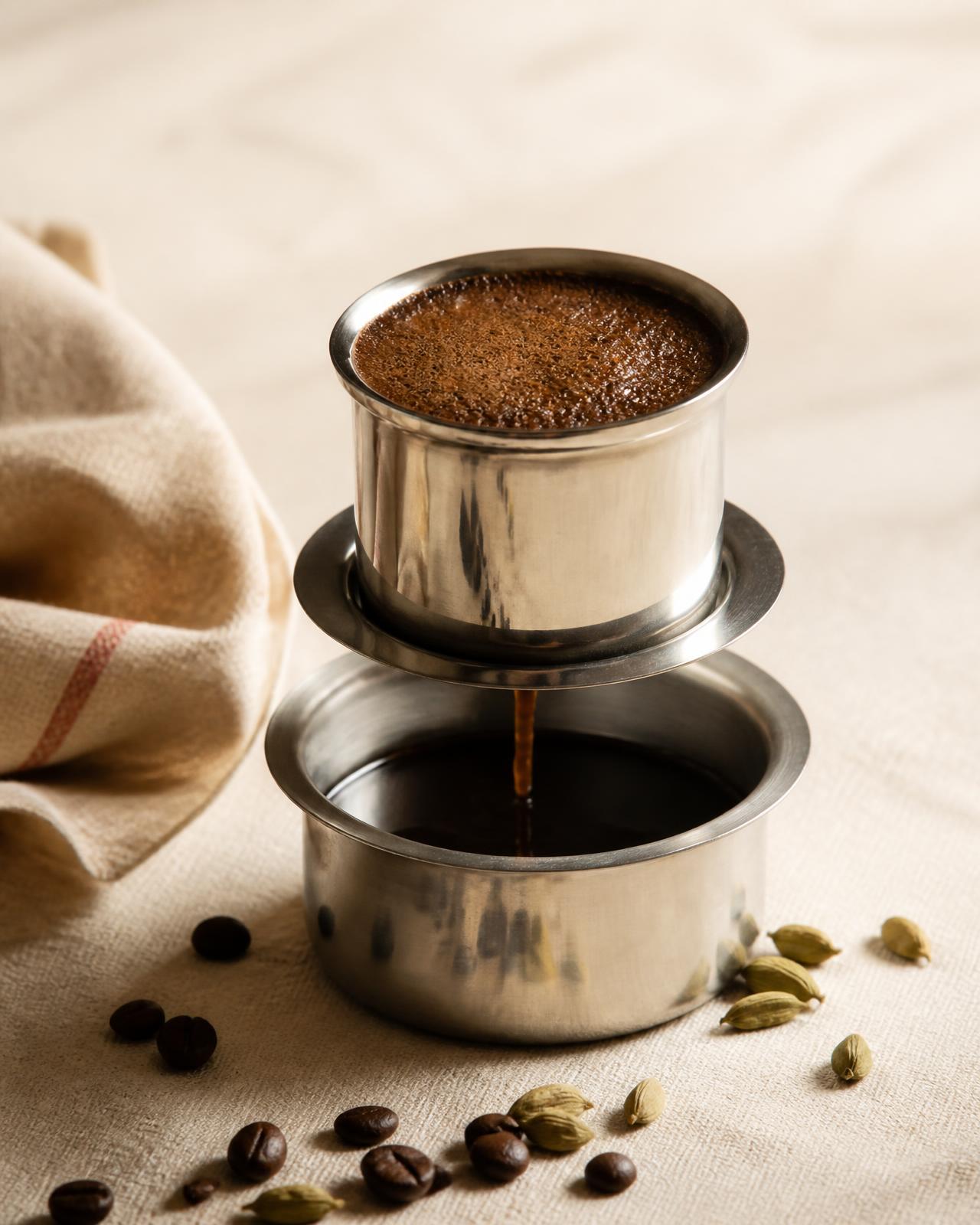 Traditional South Indian coffee filter with dark decoction dripping into the lower chamber